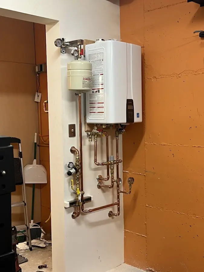 Plumbing technician inspecting water heater connections in Littlefield